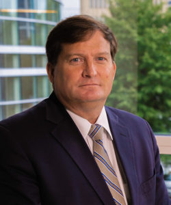 Headshot of Kirk Pope, a caucasian man with short borwn hair wearing a dark blue suit.