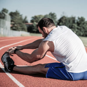 A man stretching on a red running track.